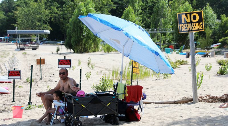 A photo of a person at the beach beside a private property sign.