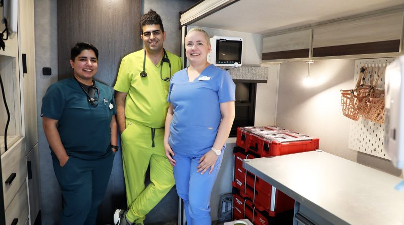Three animal care staff pose in a mobile unit.