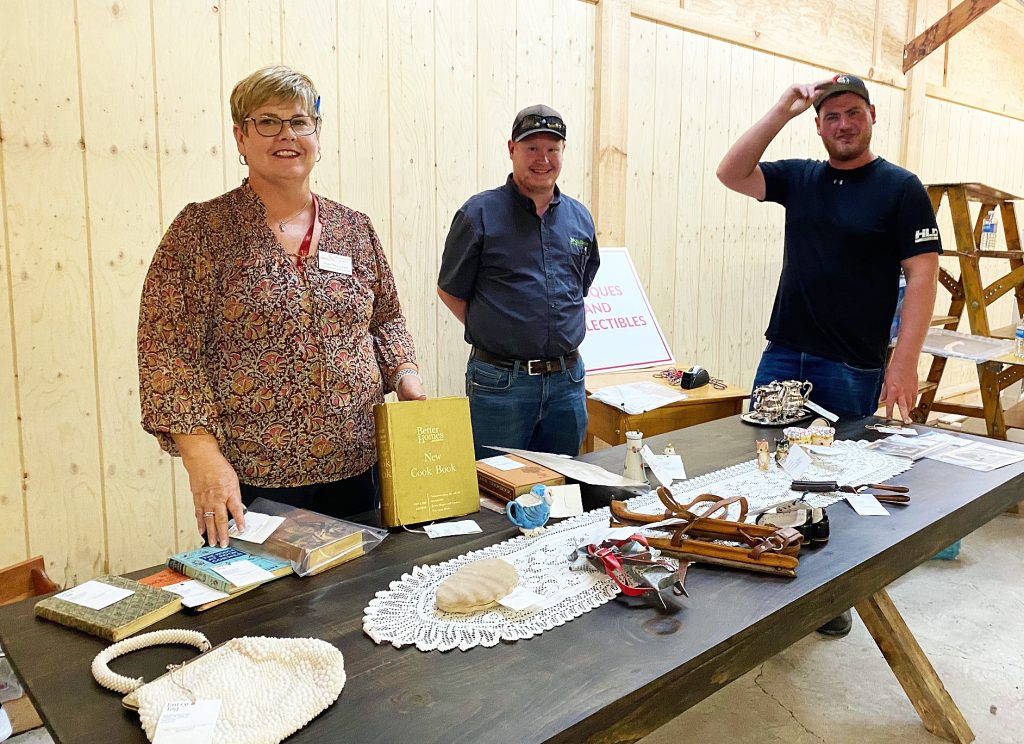 Three people pose with antiques.