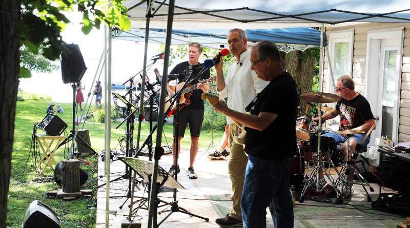 A photo of a band performing under a shade tent.
