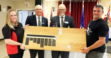 Four people hold a really big award.