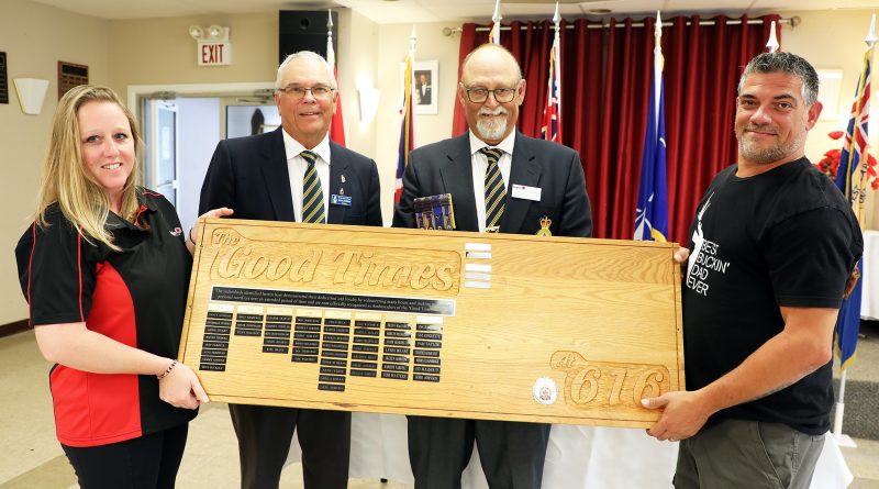 Four people hold a really big award.