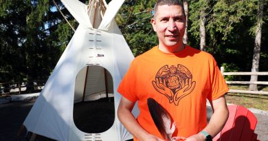 A man stands in front of a tipi.