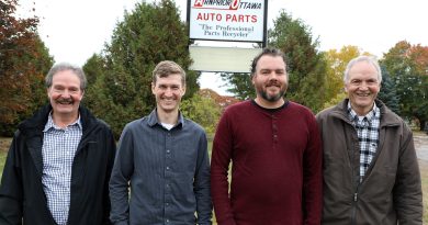 Four people stand in front of a sign.