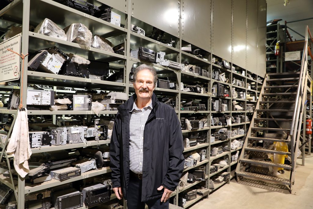 A man stands in front of a lot of parts.
