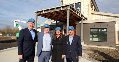 Four people pose in front of an under construction building.