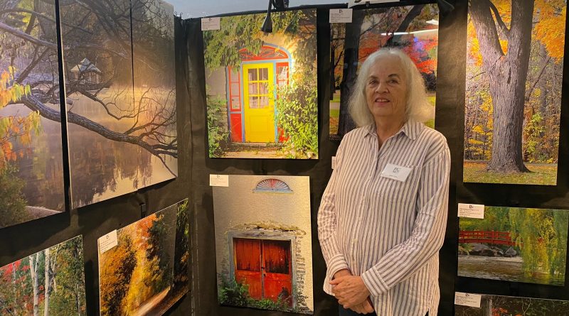 A woman stands in front of her art.
