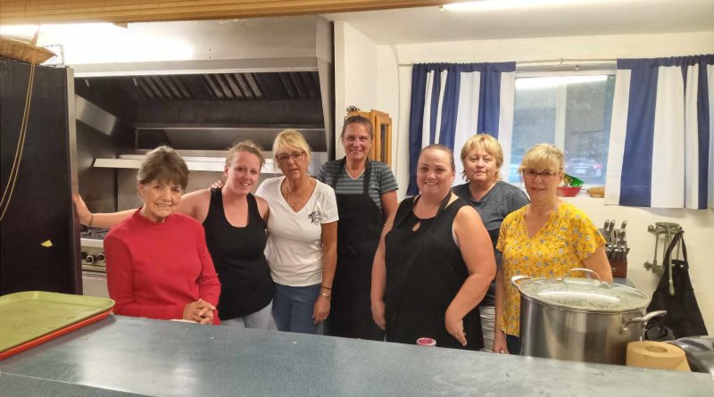 A group of people pose in a kitchen.