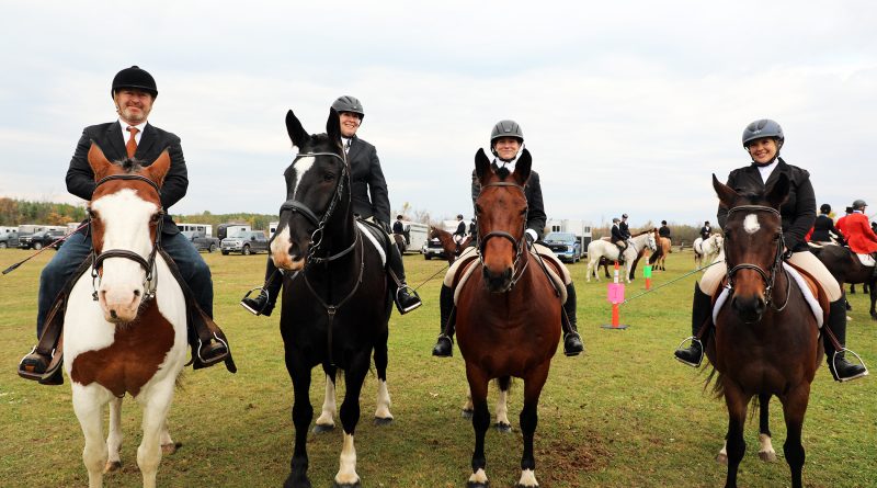 Four people on horses pose for a photo.
