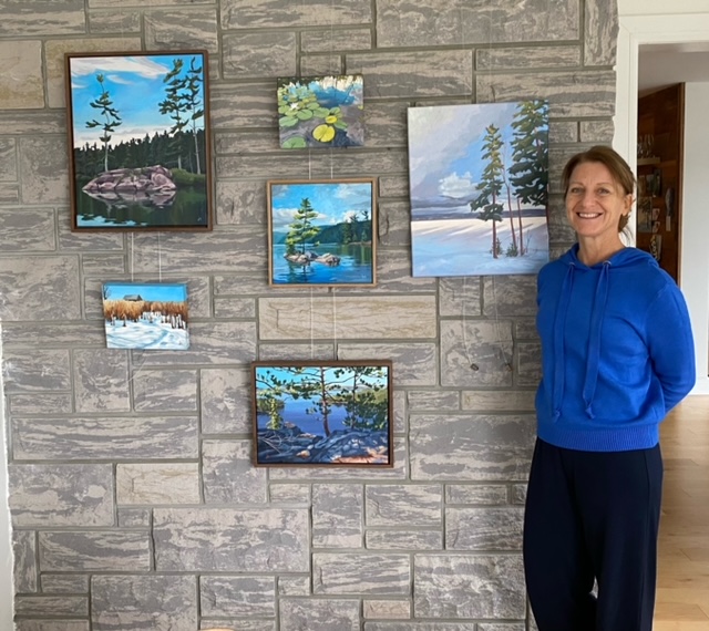 A woman poses beside her art.