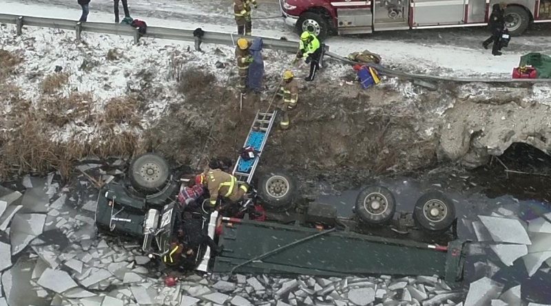 A photo of rescuers working on a dump truck in the water.