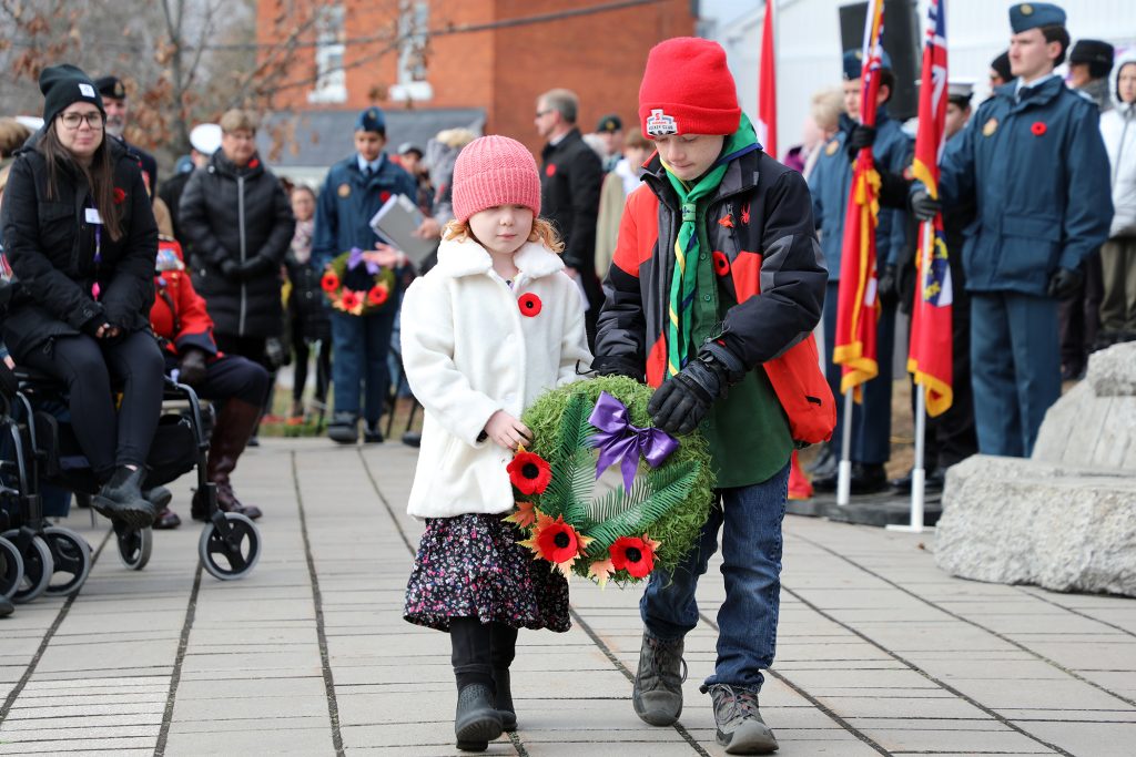 Two kids bring a wreath to the memorial.