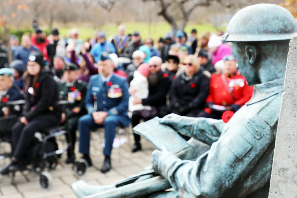 A photo of a statue and people attending a ceremony.