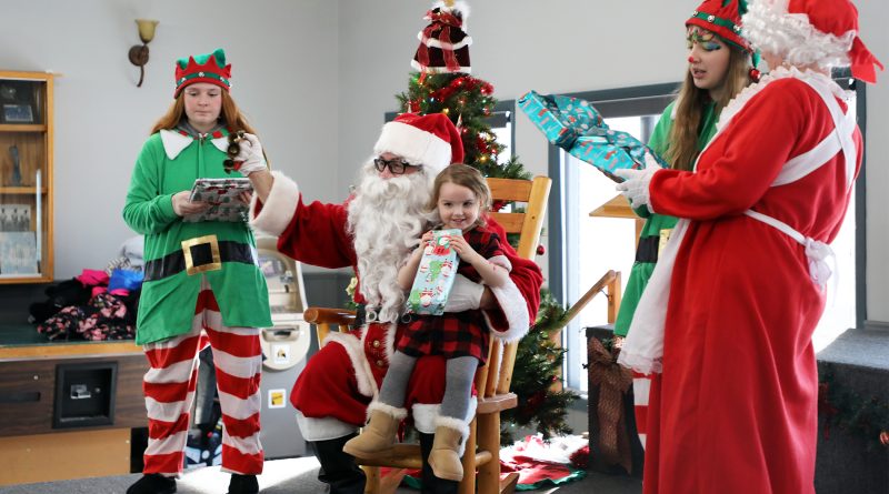 Santa, some elves and a little one enjoy a Christmas party.