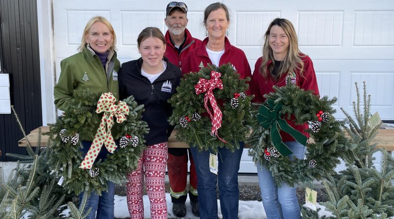 A group of people pose with wreaths.