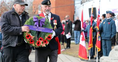 Two people lay a wreath at a memorial.