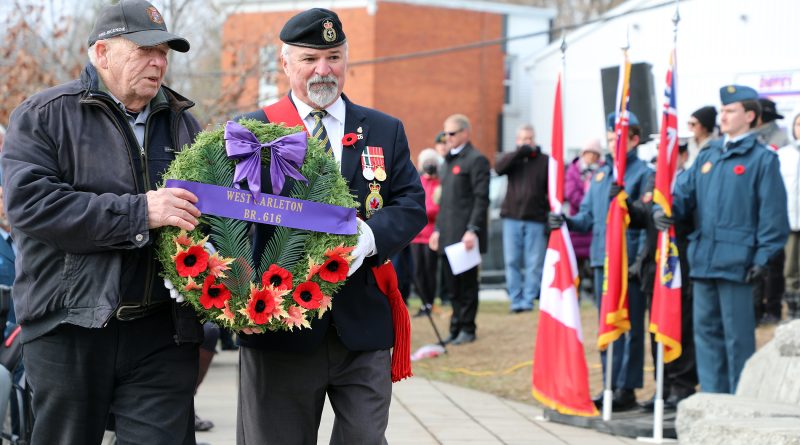 Two people lay a wreath at a memorial.