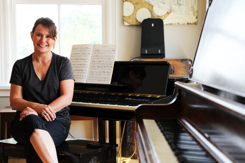 A music teacher sits at a piano.