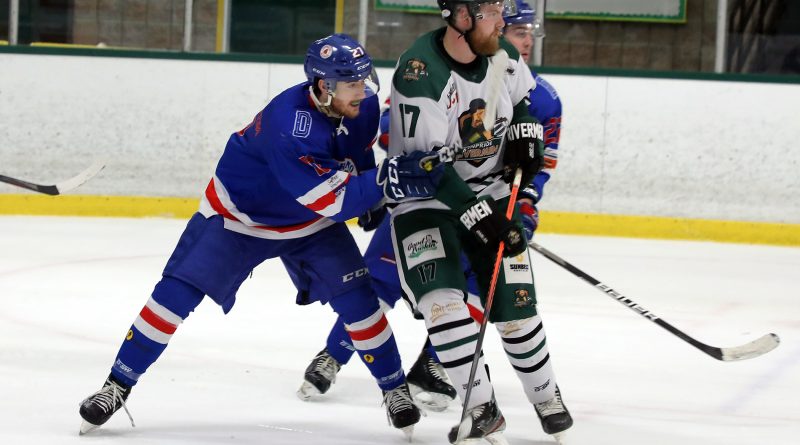 Two players battle for a puck in a hockey game.
