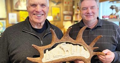 Two men pose with a carving.