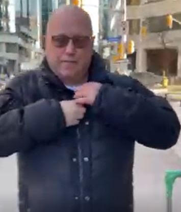 A bald man zips his jacket.
