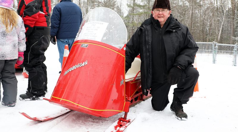 A man poses beside a snowmobile.