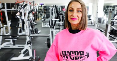 A woman poses for a photo in a gym.