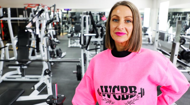 A woman poses for a photo in a gym.