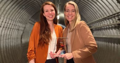 Two people stand in a tunnel with an award.