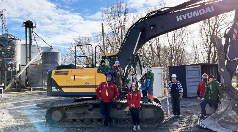 Scouts pose on an excavator.