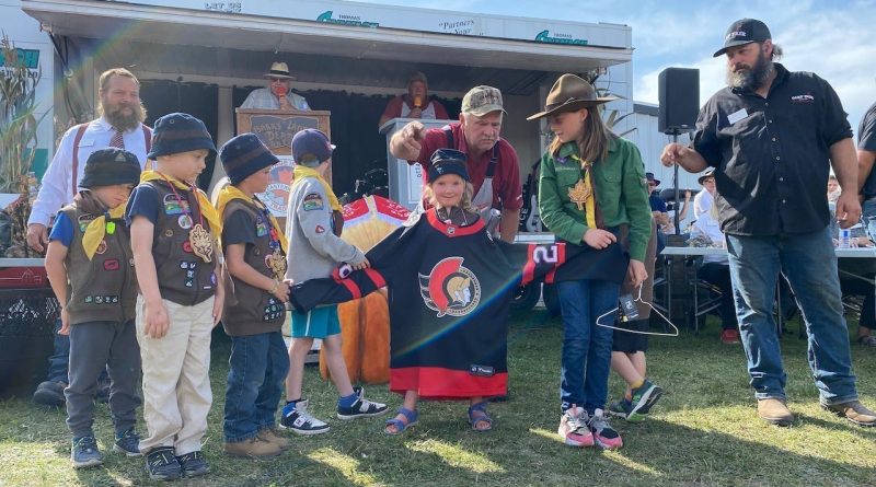 A group of kids show off a hockey jersey.
