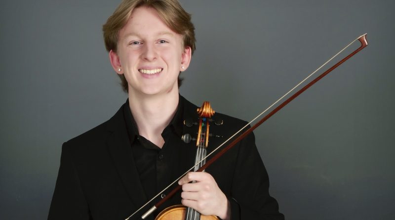 A photo of a youth holding a violin.