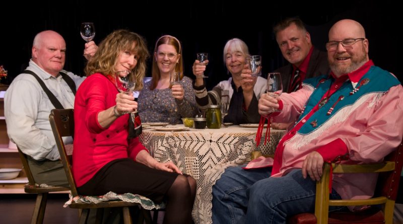 A group poses for a photo around a dinner table.