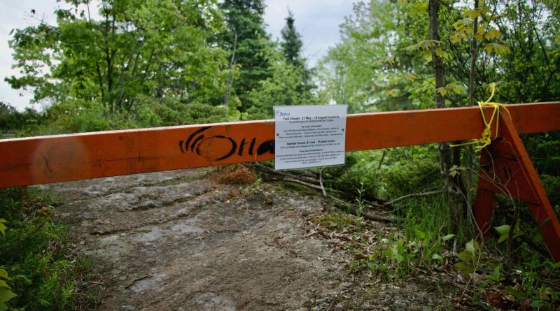 A photo of a barrier in front of a trail.