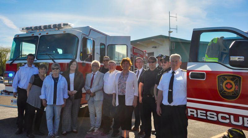 A group of people pose in front of a fire truck.