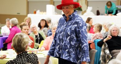 A woman models spring fashions in a packed hall.