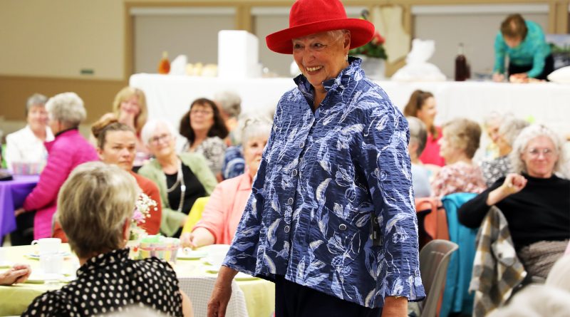 A woman models spring fashions in a packed hall.
