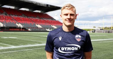 A soccer player poses for a photo inside a stadium.