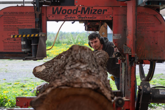 A photo of a person working a sawmill.