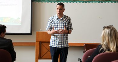 A mayor speaks at the front of a room.