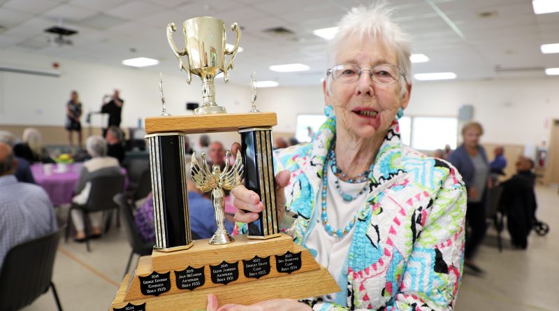 A woman holds a trophy.