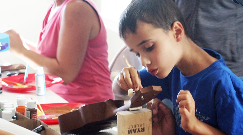 A boy works on a ukulele.