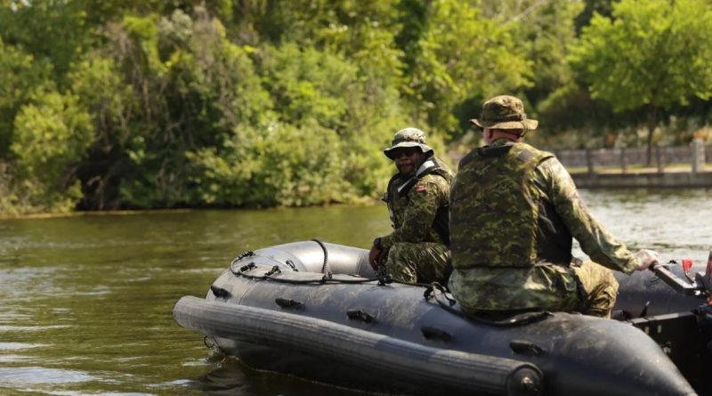 Two soldiers operate a small rubber boat.