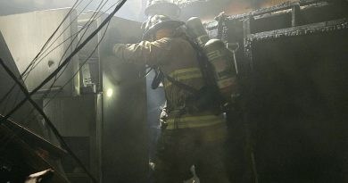 A firefighter works in a burnt kitchen.