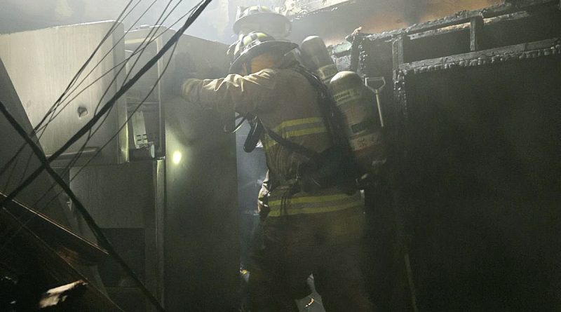 A firefighter works in a burnt kitchen.