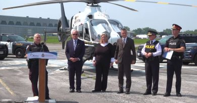 People pose in front of a helicopter.