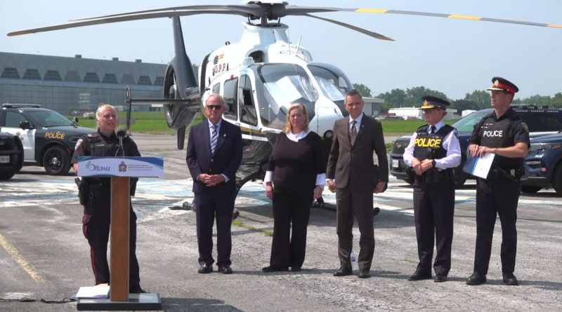 People pose in front of a helicopter.