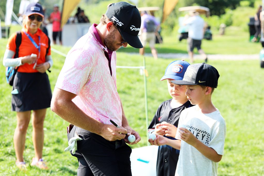 A player signs a golf ball for some young fans.