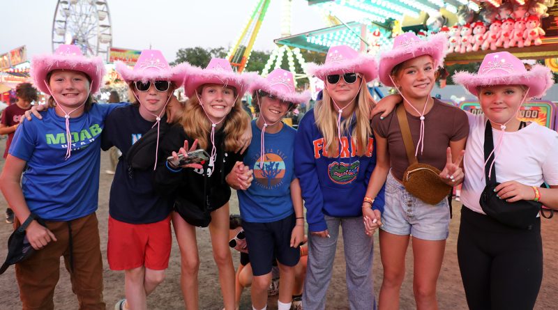 Kids in pink cowboy hats pose for a photo.