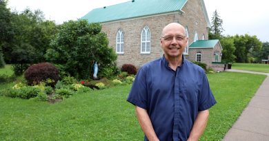 A priest poses in front of a church.